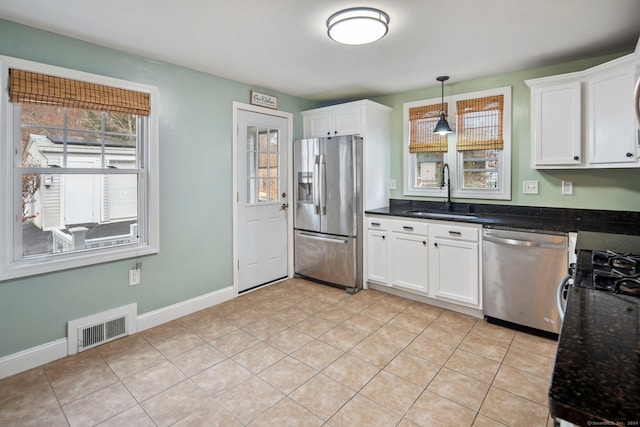 kitchen with sink, white cabinets, light tile patterned floors, and appliances with stainless steel finishes