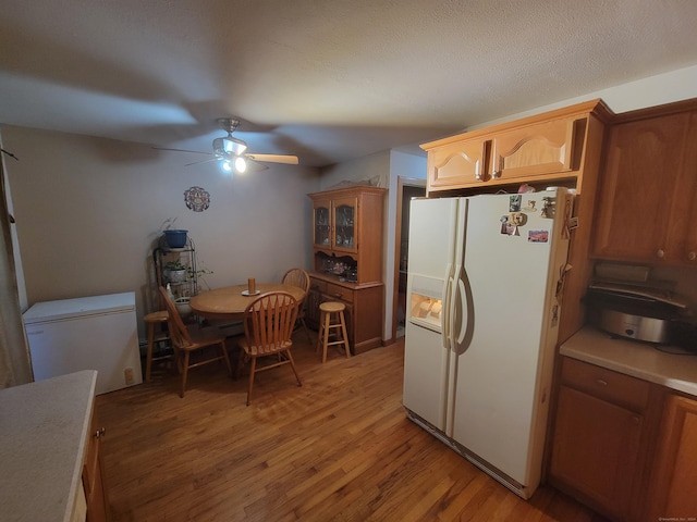 kitchen with refrigerator, a textured ceiling, ceiling fan, light hardwood / wood-style flooring, and white fridge with ice dispenser