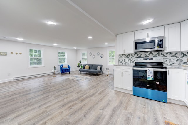 kitchen featuring white cabinets, plenty of natural light, appliances with stainless steel finishes, and a baseboard heating unit