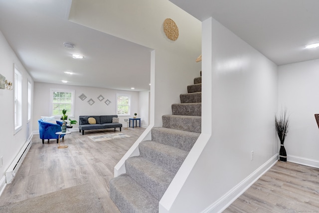 stairway featuring hardwood / wood-style flooring and a baseboard heating unit