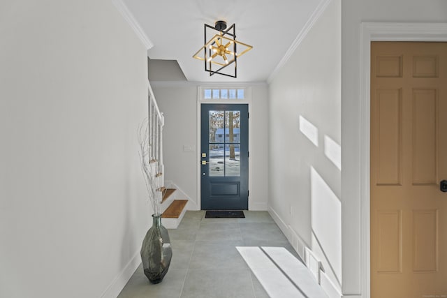 tiled entryway featuring crown molding and a chandelier