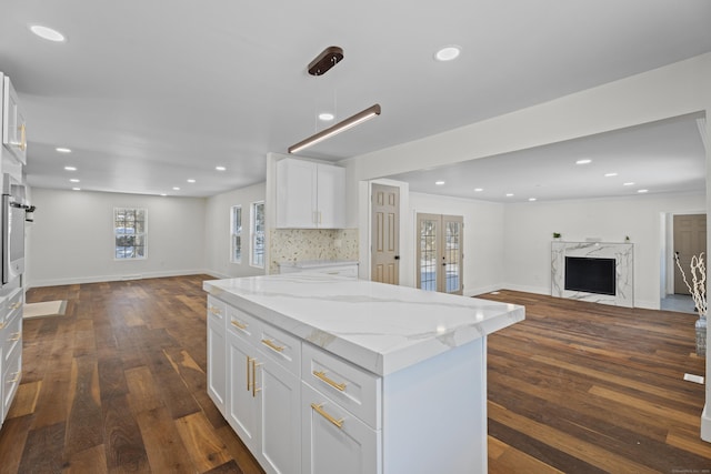 kitchen featuring light stone counters, dark hardwood / wood-style floors, a fireplace, and white cabinets