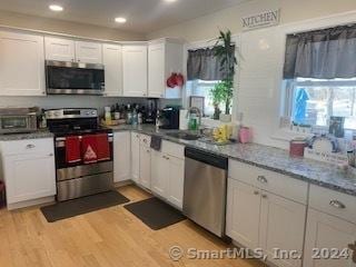 kitchen featuring stainless steel appliances, white cabinetry, and light hardwood / wood-style flooring