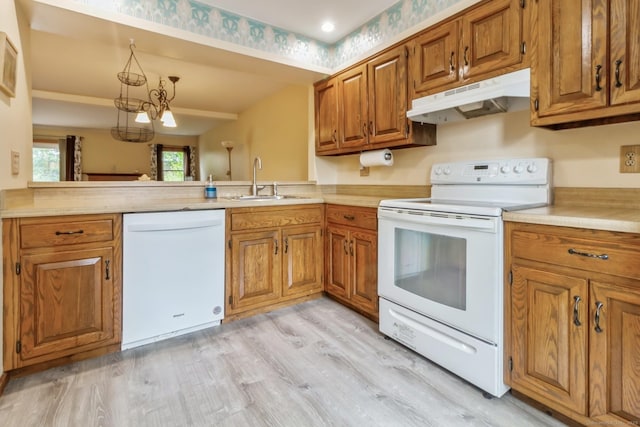 kitchen featuring white appliances, under cabinet range hood, brown cabinets, and light countertops