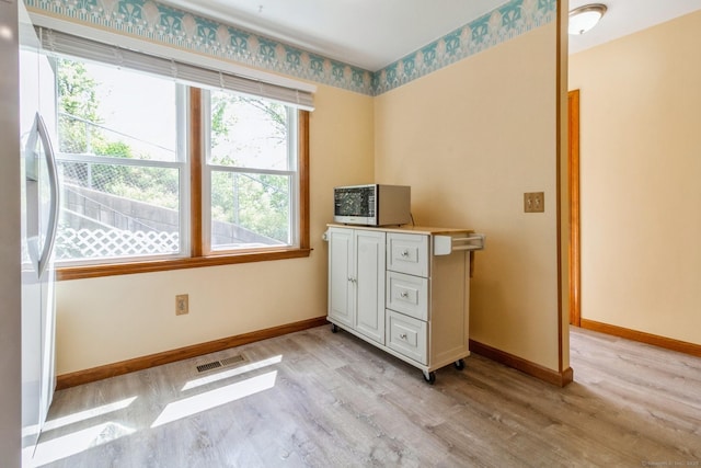 bedroom featuring light wood-style flooring, baseboards, and fridge with ice dispenser