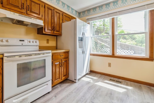 55 Mill Plain Rd Unit 20-5, Danbury, CT 06811 - kitchen featuring white appliances, under cabinet range hood, light wood-style flooring, and brown cabinetry