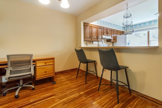 kitchen with dark wood finished floors, a kitchen bar, and baseboards