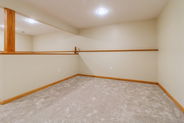 spare room with carpet, baseboards, and beamed ceiling