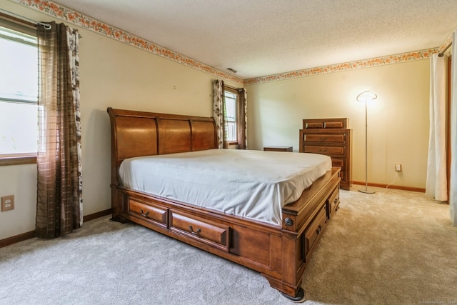 bedroom with light carpet, baseboards, and a textured ceiling