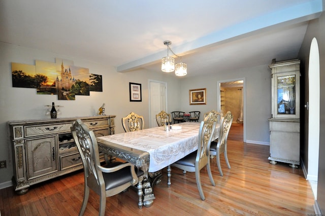 dining room featuring hardwood / wood-style flooring, beamed ceiling, and a chandelier