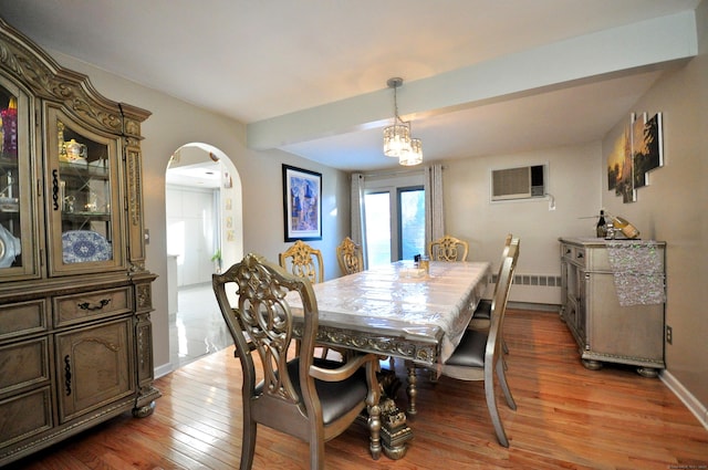 dining area featuring a wall unit AC, beam ceiling, hardwood / wood-style flooring, an inviting chandelier, and radiator heating unit