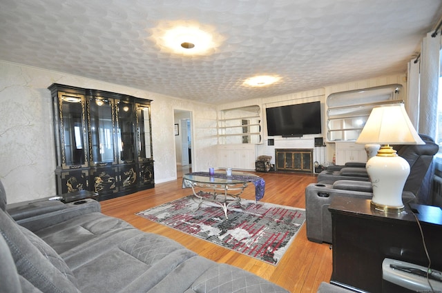 living room featuring built in features, wood-type flooring, and a textured ceiling