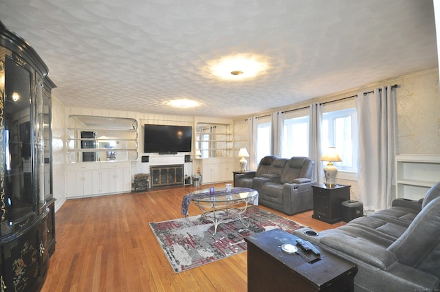 living room featuring built in features, wood-type flooring, and a textured ceiling