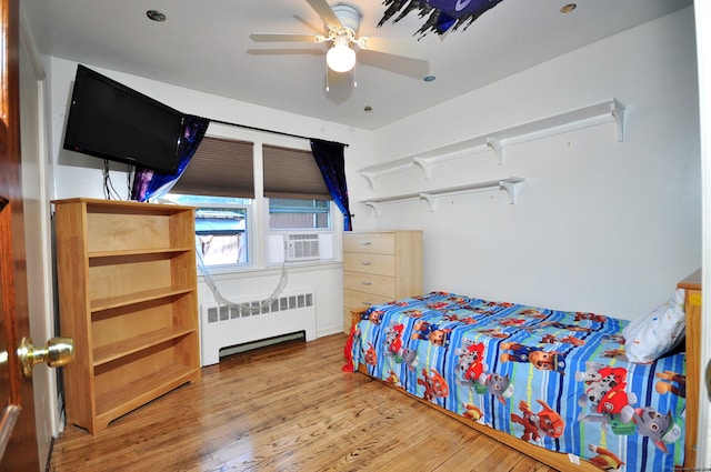 bedroom featuring radiator heating unit, ceiling fan, and wood-type flooring