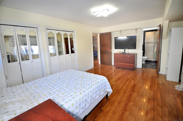 bedroom with hardwood / wood-style flooring, ensuite bath, and two closets