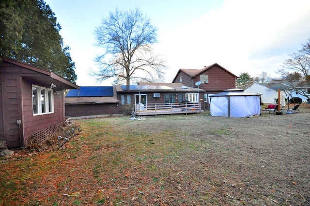 rear view of house with a pool side deck and solar panels