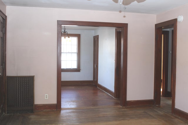 corridor with dark wood-type flooring and a notable chandelier