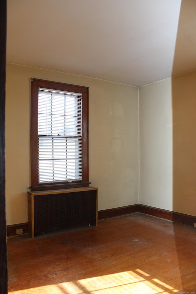 unfurnished room with wood-type flooring and radiator heating unit