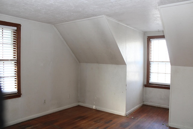 bonus room featuring a textured ceiling, dark wood-type flooring, and vaulted ceiling