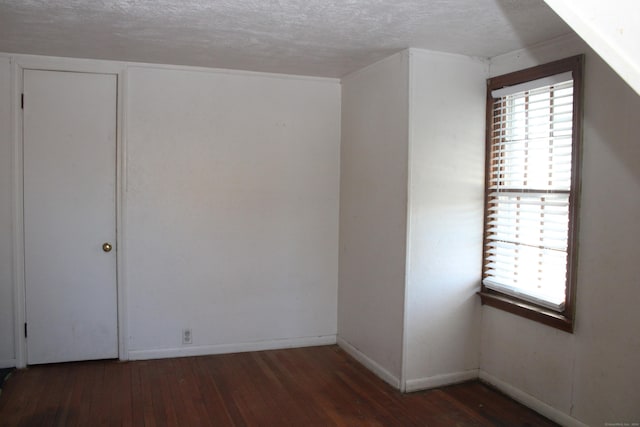 unfurnished room featuring a textured ceiling, a wealth of natural light, and dark hardwood / wood-style floors