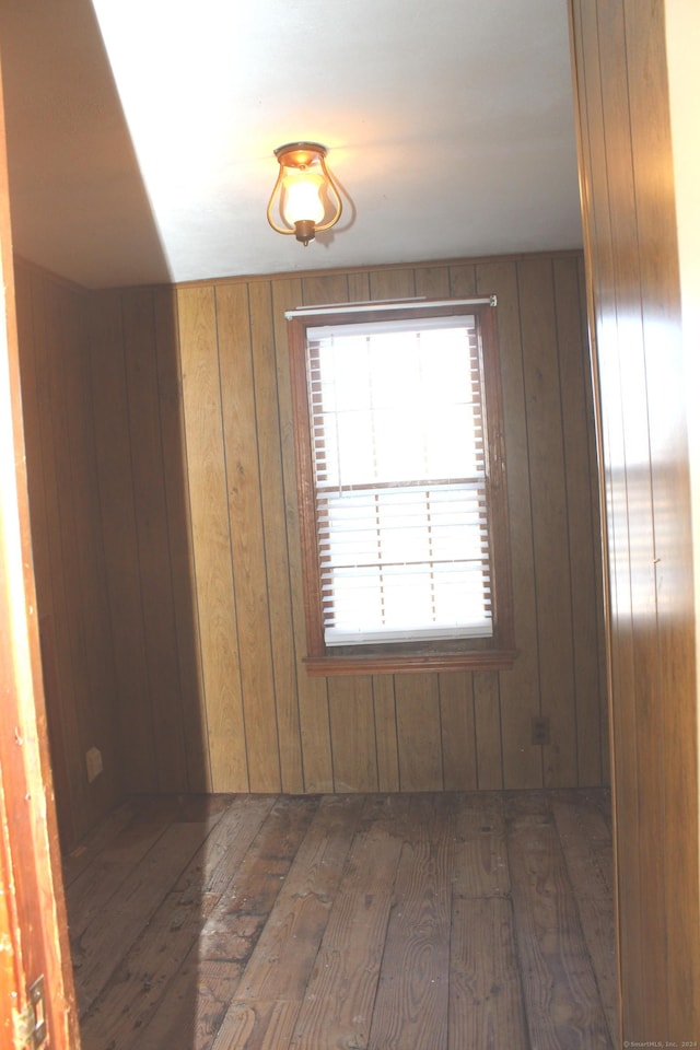 unfurnished room featuring wooden walls and dark hardwood / wood-style flooring