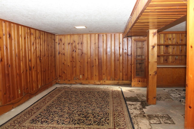 basement featuring a textured ceiling and wooden walls