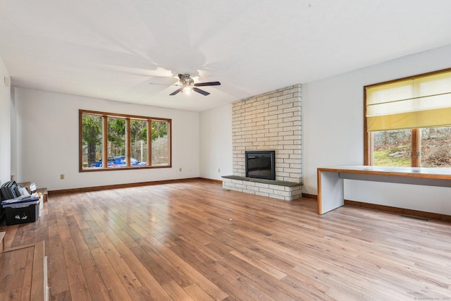 unfurnished living room with light hardwood / wood-style floors, a brick fireplace, and ceiling fan
