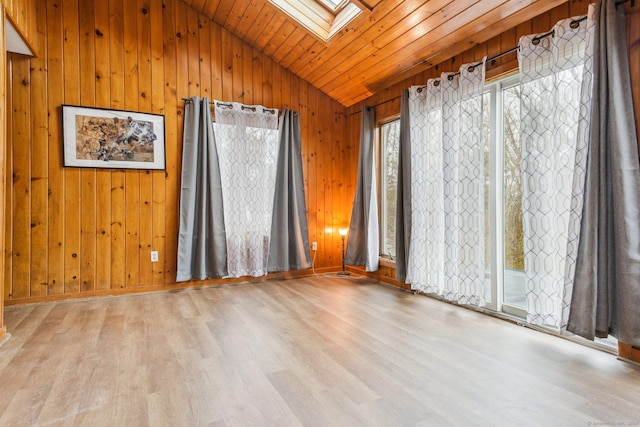 unfurnished room featuring light hardwood / wood-style flooring, lofted ceiling with skylight, wooden ceiling, and wood walls