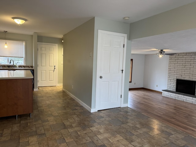 unfurnished living room with a fireplace, ceiling fan, and sink