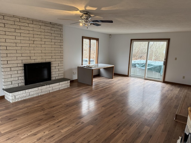 unfurnished living room with ceiling fan, a large fireplace, and dark hardwood / wood-style floors