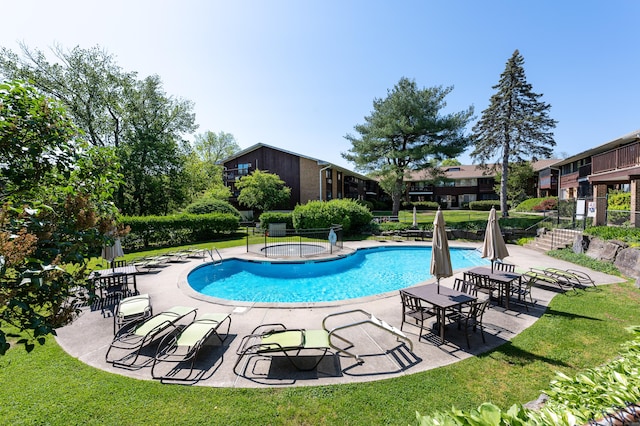 view of pool with a patio area, a lawn, and a community hot tub