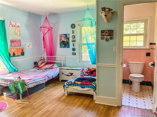 bedroom featuring hardwood / wood-style flooring and tile walls