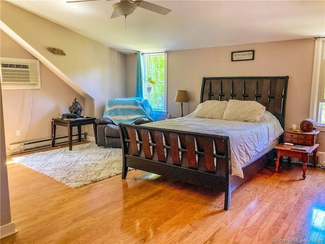 bedroom with a wall mounted air conditioner, ceiling fan, wood-type flooring, and multiple windows