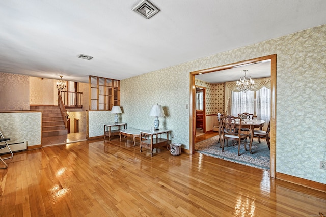 living area with hardwood / wood-style flooring, a notable chandelier, and baseboard heating