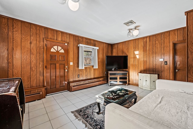 living room featuring light tile patterned flooring, baseboard heating, and wooden walls