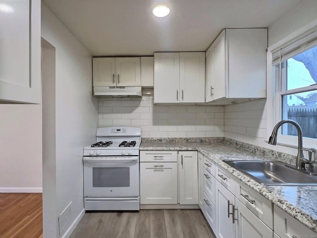 kitchen featuring white cabinets, decorative backsplash, white gas range oven, and sink