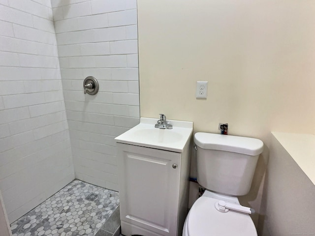 bathroom with toilet, vanity, and tiled shower