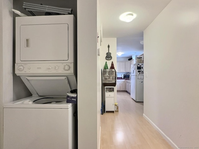 laundry area with light hardwood / wood-style flooring and stacked washer / drying machine