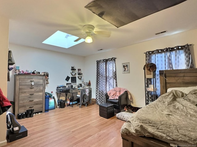 bedroom featuring ceiling fan, wood-type flooring, and a skylight