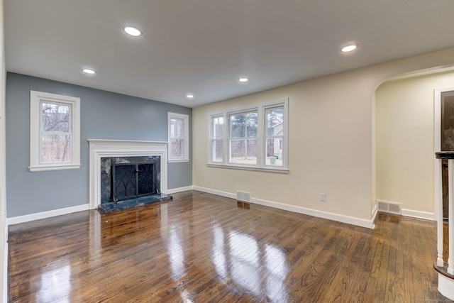 unfurnished living room featuring a high end fireplace and dark wood-type flooring