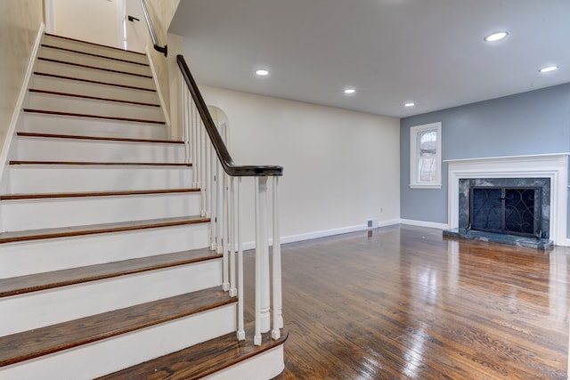 staircase with hardwood / wood-style flooring and a premium fireplace