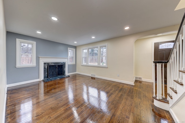 unfurnished living room with a fireplace, plenty of natural light, and dark hardwood / wood-style floors