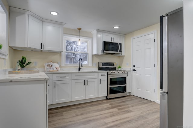 kitchen with sink, hanging light fixtures, light hardwood / wood-style floors, white cabinetry, and stainless steel appliances