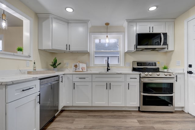 kitchen with sink, white cabinets, pendant lighting, and appliances with stainless steel finishes