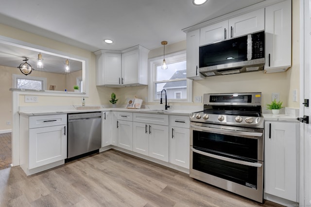 kitchen featuring white cabinets, stainless steel appliances, hanging light fixtures, and sink