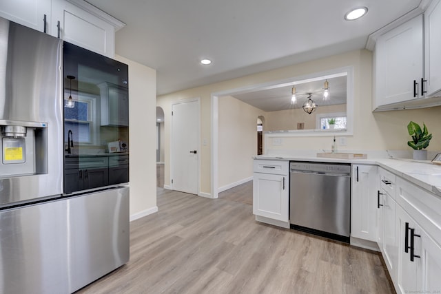 kitchen featuring light stone counters, stainless steel appliances, light hardwood / wood-style flooring, white cabinetry, and hanging light fixtures