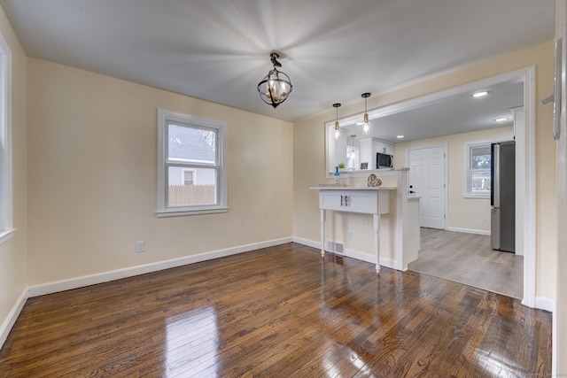 interior space with dark hardwood / wood-style floors, a healthy amount of sunlight, kitchen peninsula, and stainless steel appliances