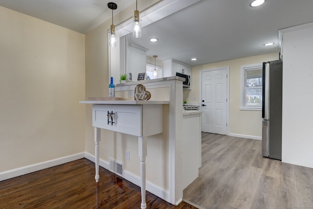 kitchen with decorative light fixtures, white cabinetry, appliances with stainless steel finishes, and light hardwood / wood-style flooring