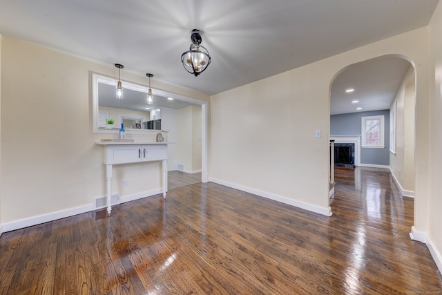 unfurnished living room featuring dark hardwood / wood-style flooring and an inviting chandelier