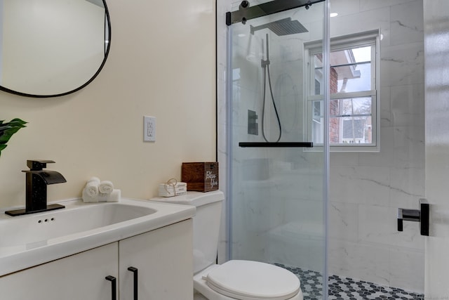 bathroom featuring a shower with door, vanity, and toilet